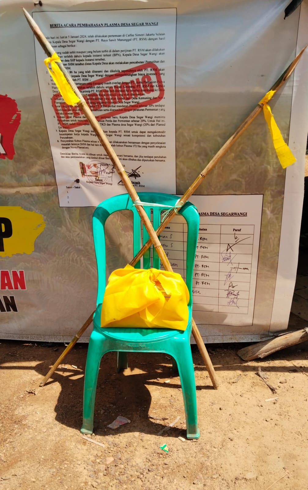 simbol kehormatan adat berupa tepak sirih yang dibalut kain kuning dengan dua batang bambu runcing terikat bersilang diletakan di tenda yang didirikan warga di jalan akses sejak 16/5/2026